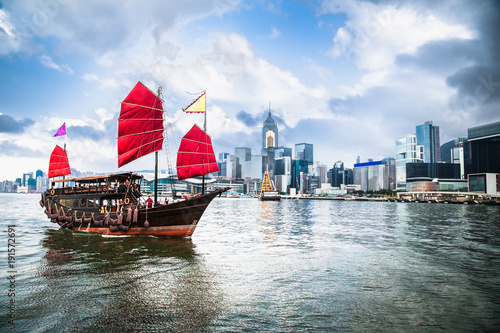 Traditional Chinese wooden sailing ship with red sails in Victoria harbor, Hong Kong.