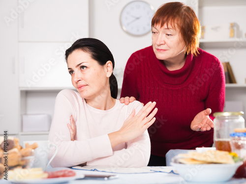 Upset woman quarrel with mother at table