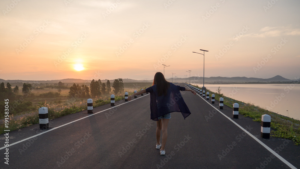 Young asian woman walking on the road at sunrise