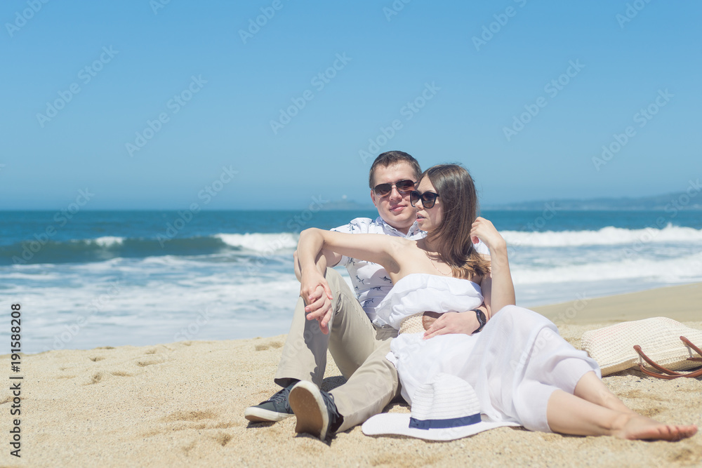 Young smiling couple sitting on the beach Young smiling couple sitting on the beach