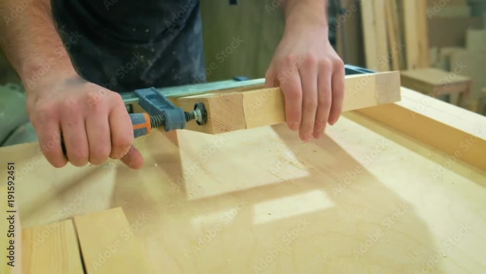 The carpenter makes a wooden stool in his workshop. Clamped the chair in a vice The carpenter makes a wooden stool in his workshop. Clamped the chair in a vice