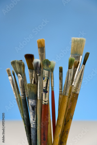Well used artists paintbrushes on a blue background