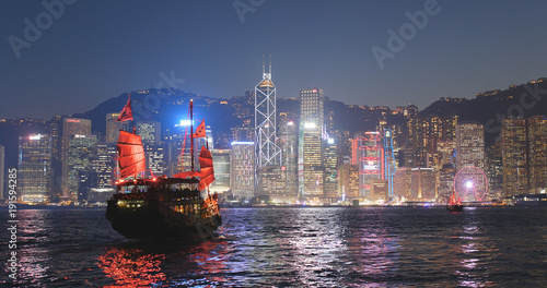 Sail junk boat travel in Victoria harbor in Hong Kong city at night