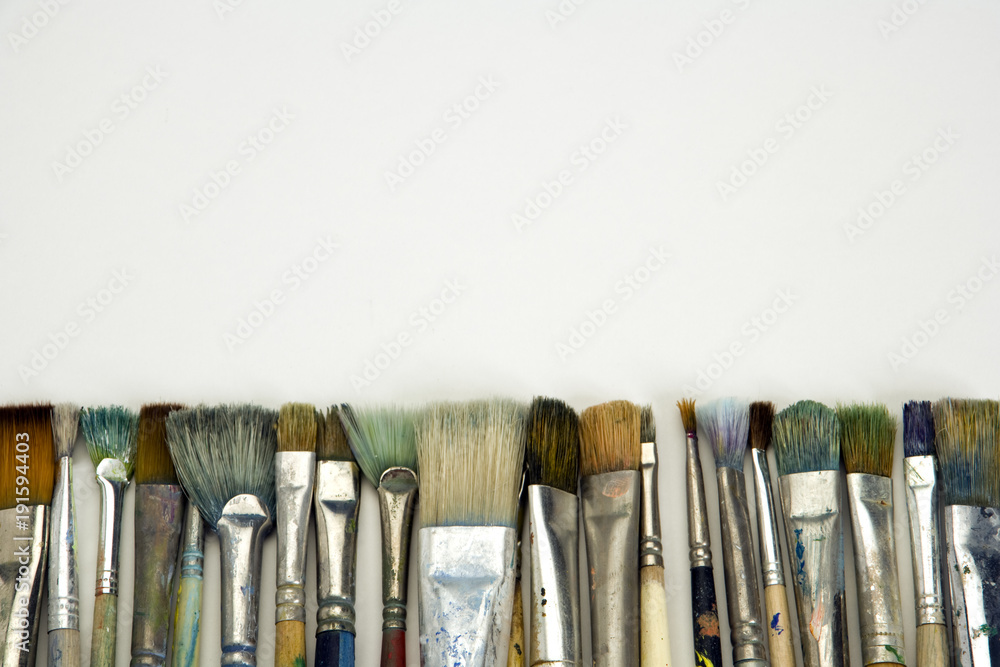 Obraz premium Well used artists paintbrushes on a white paper background