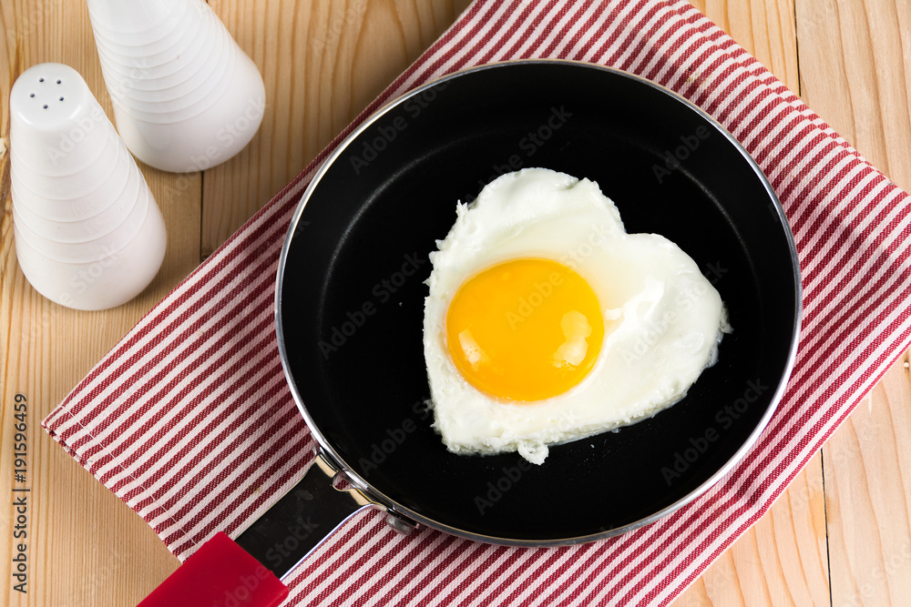 Fried egg in heart shape on pan