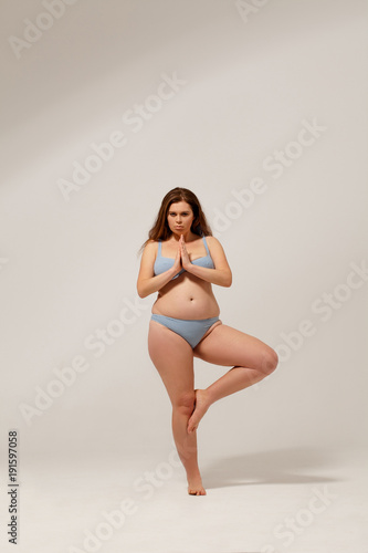 Fat brunette female in underwear. Posing on camera.