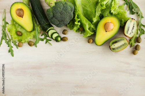 Avocado, broccoli cabbage, cucumber and olives on light background