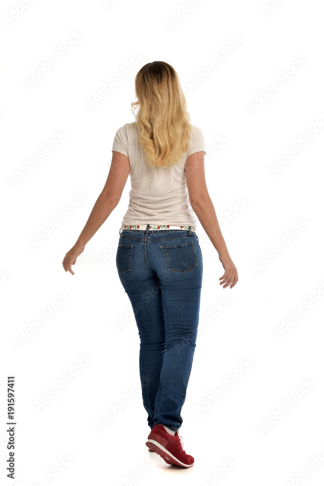 Obraz premium full length portrait of blonde lady wearing simple white shirt and jeans, standing pose isolated on white studio background.