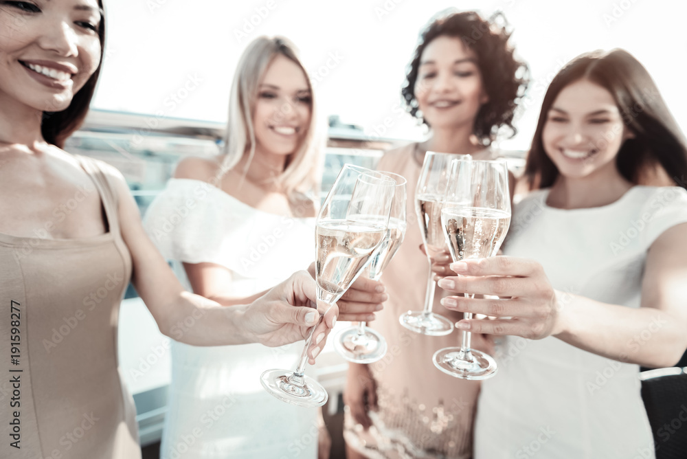 Sparkling wine. Selective focus of glasses with champagne being held by positive attractive young women while having a celebration Sparkling wine. Selective focus of glasses with champagne being held by positive attractive young women while having a celebration