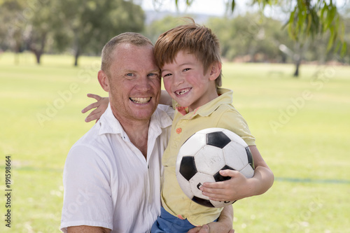 young happy father carrying on his back excited 7 or 8 years old son playing together soccer football on city park garden posing sweet and loving © Wordley Calvo Stock