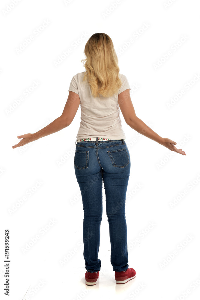 full length portrait of blonde lady wearing simple white shirt and jeans, standing pose isolated on white studio background. full length portrait of blonde lady wearing simple white shirt and jeans, standing pose isolated on white studio background.