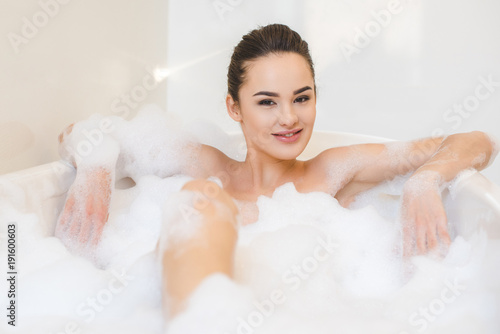 attractive young woman taking bath with foam at home