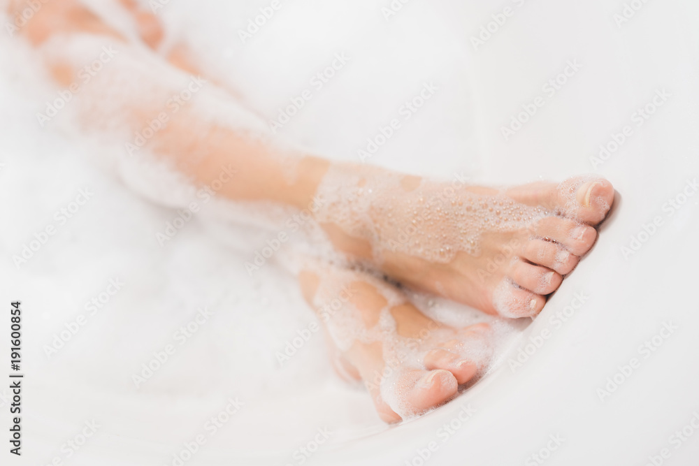 partial view of female legs in bath with foam partial view of female legs in bath with foam