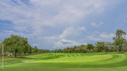 The green grass on golf course with blue cloud sky background