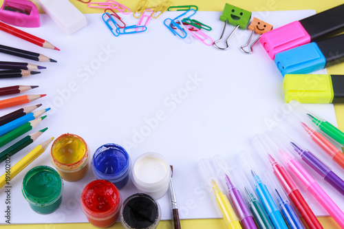 paper with colored crayons, brush, pencils and paints on yellow background. Top view . Flat lay image.Working desk table concept.