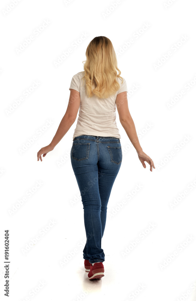 full length portrait of blonde lady wearing simple white shirt and jeans, standing pose isolated on white studio background. full length portrait of blonde lady wearing simple white shirt and jeans, standing pose isolated on white studio background.