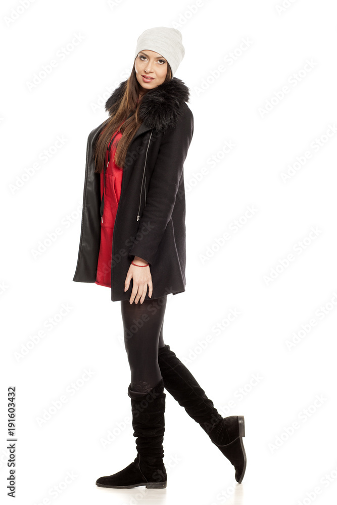 Profile of young woman in winter clothess walking on white background