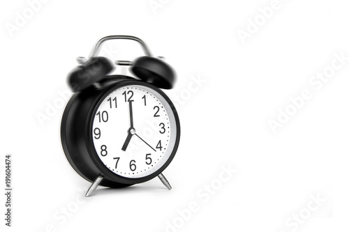 Black Alarm Clock bell classic vintage style running at alarm. To wake up is Life beginning of the day After sleep at time 7:00 a.m. Front a 45 degree angle. Isolated on white background.