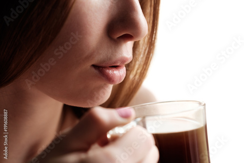 redhead woman holding cup of coffe and sniffing it on white background copy space