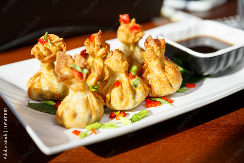 Portion of six fried wontons on a plate with sticks Portion of six fried wontons on a plate with sticks
