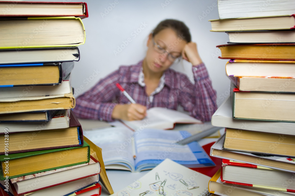 A student in glasses studies, surrounded by books.. Woman science work. 