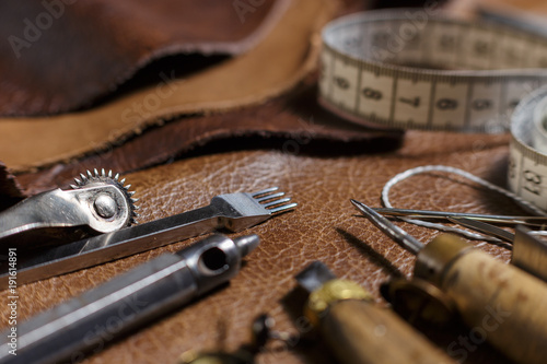 Furniture assembly parts and tools on a cow leather samples in the in the craftman's workshop. Close-up
