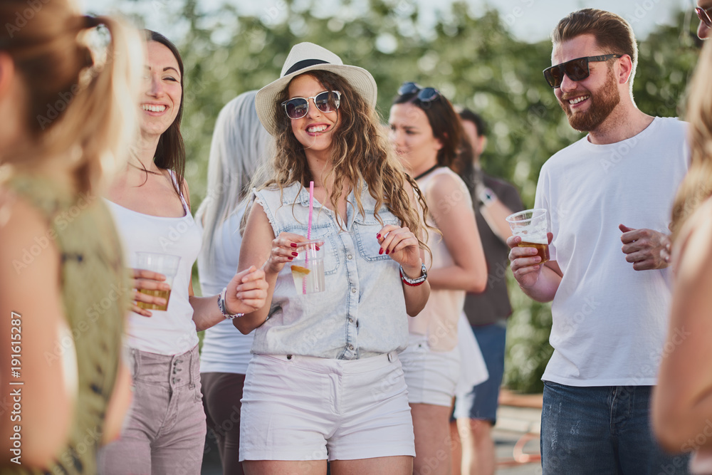 Group of people standing and drinking at the summer outdoor party 