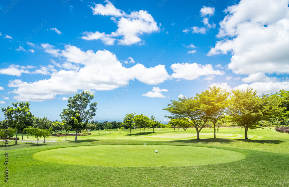 Green grass and trees at golf course with blue cloud sky background 