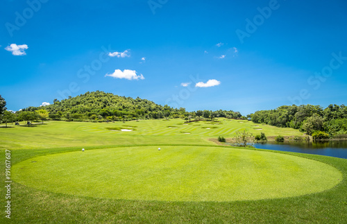 Green grass and trees at golf course with blue cloud sky background 