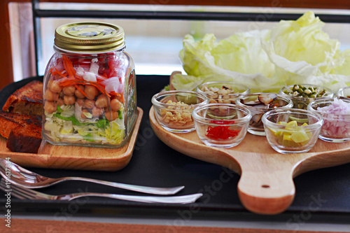 Salad in a Jar is layered with greens, with shredded carrots, chickpea, onion and tomato photo
