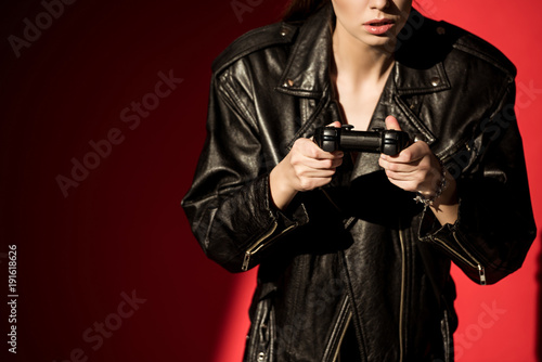 cropped view of girl in black leather jacket playing video game with joystick