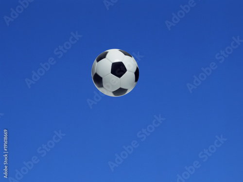 A soccer ball shot in the air with blue sky background