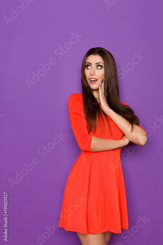 Surprised Beautiful Young Woman In Red Mini Dress Is Looking Away