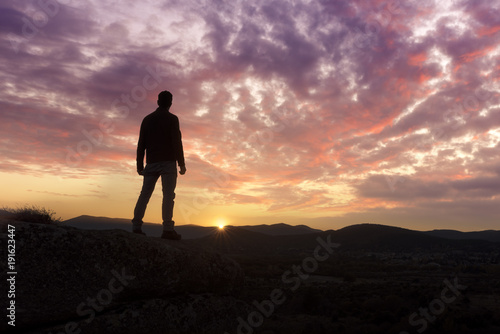 A young man traveler standing enjoy with beautiful sunset on top of the mountain.
