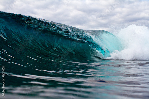 moody blue wave crashing over shallow reef