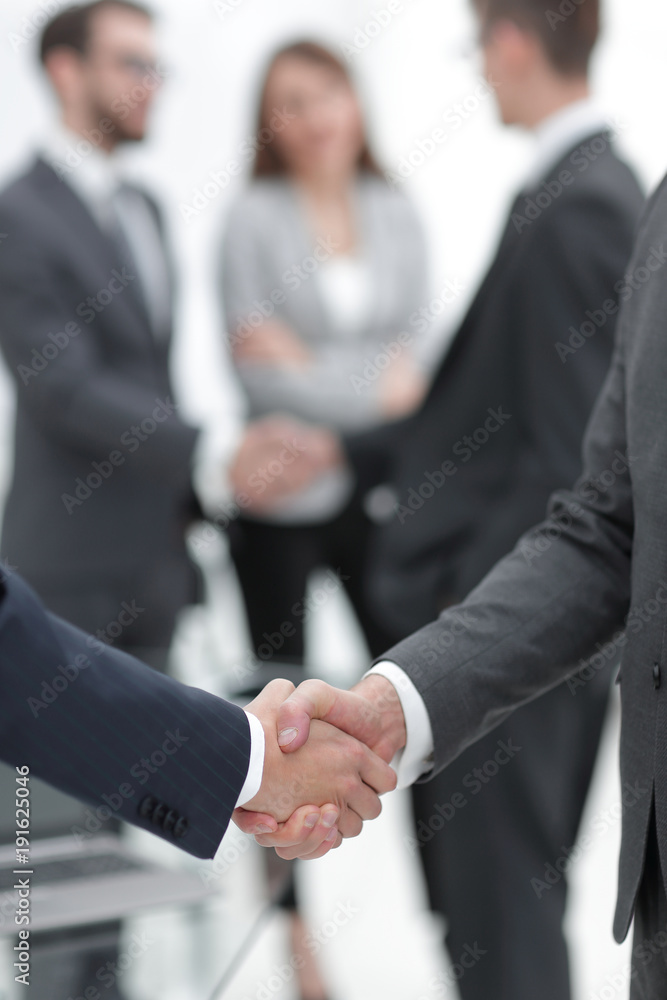 Fototapeta premium Two businessmen shaking hands with colleagues on background.