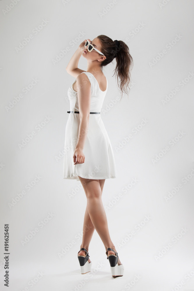 fashion portrait of a woman. a young beautiful girl in a light white dress posing in the Studio. Sunglasses. fashion portrait of a woman. a young beautiful girl in a light white dress posing in the Studio. Sunglasses.