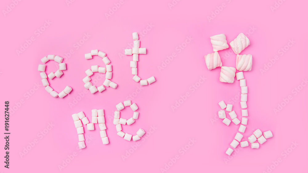 Marshmallows on pink background with sign in English Eat me. Flat lay or top view. Background or texture of colorful mini marshmallows. Winter food background concept. Marshmallows on pink background with sign in English Eat me. Flat lay or top view. Background or texture of colorful mini marshmallows. Winter food background concept.