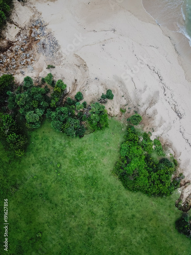 Beach on the beach of the island of Bali. Pink sand and green grass. The view from above is taken from the drone.