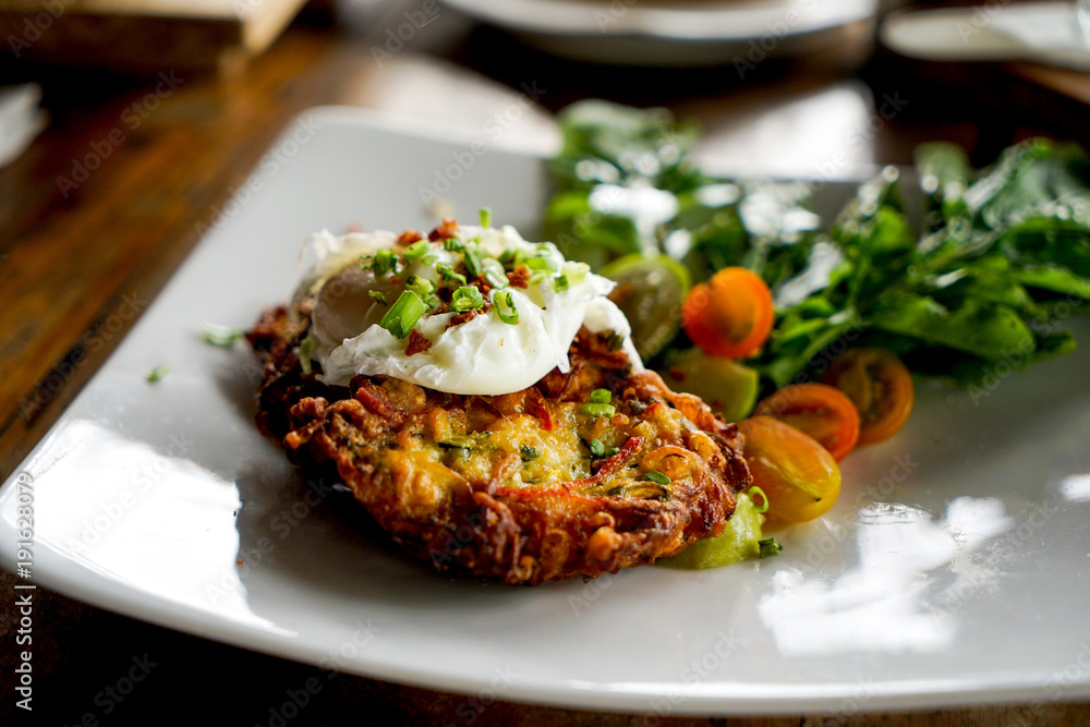 Egg poached with potato hash brown and summer salad. Close-up shot Egg poached with potato hash brown and summer salad. Close-up shot