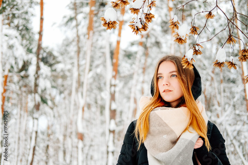 Attractive blond young adult woman walking through winter forest
