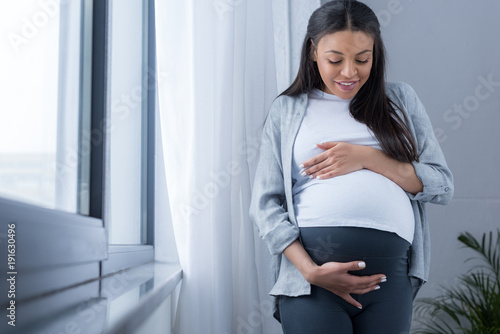 african american pregnant woman looking at her belly