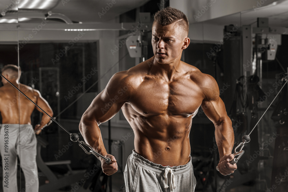 Fototapeta premium Brutal strong athletic men pumping up muscles and train in gym workout bodybuilding concept background