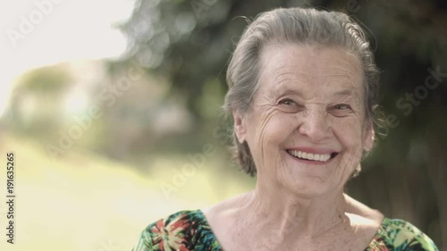 Old woman smiling outside during the day. photo