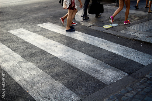 Zebra crossing, with 3 stripes and legs crossing, in Rome (Italy)