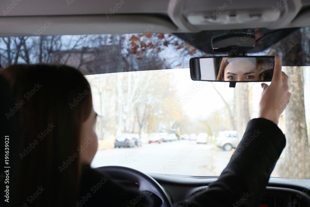 Woman adjusting rear view mirror in car Woman adjusting rear view mirror in car