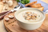 Bowl with delicious mushroom soup on wooden table