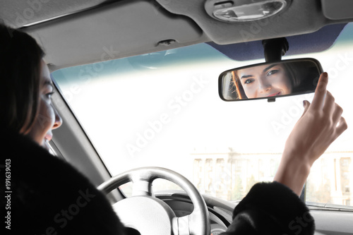 Woman adjusting rear view m...
