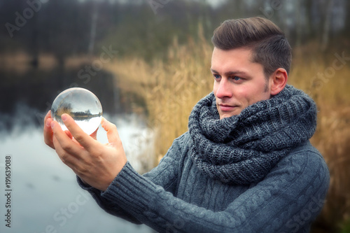 Canvas Print blond man in front of lake holding a glass ball