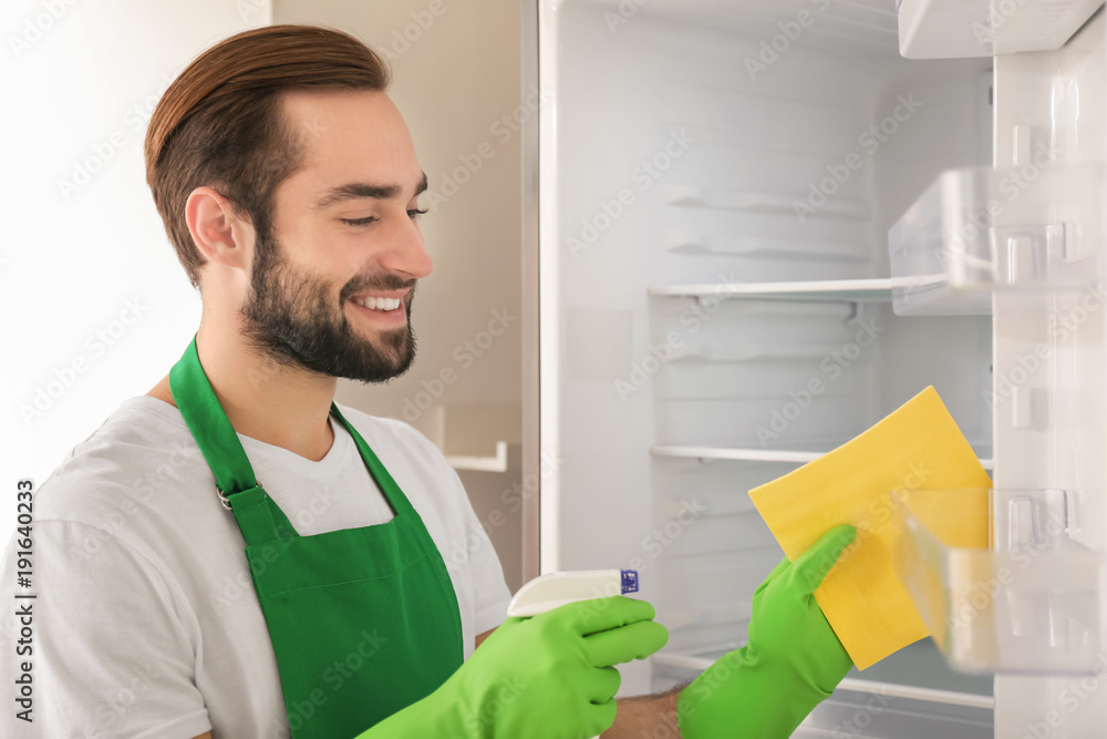 Man cleaning empty refrigerator in kitchen Man cleaning empty refrigerator in kitchen